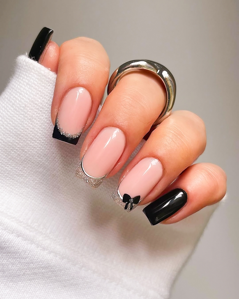 Zwarte French manicure met zilveren glitter en een zwart strikje